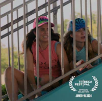 two women sitting on a railing with hats on their heads